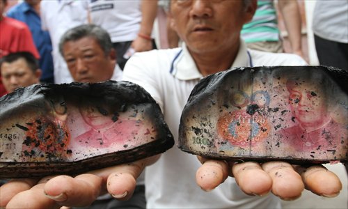 Zheng Chuanying shows the burnt bank notes on July 2. Photo: CFP