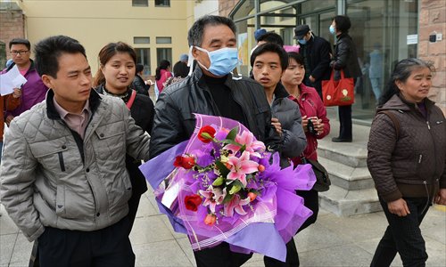 A man walks out of the Shanghai Public Health Clinical Center with his family Sunday. He was one of three male patients who got discharged from the hospital after being treated for H7N9 bird flu. Photo: Xinhua  