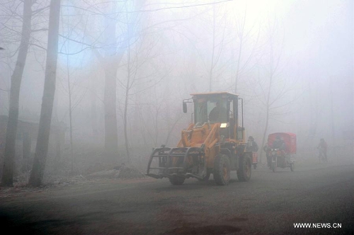  Vehicles move on a street in dense fog in Baoding, north China's Hebei Province, Jan. 12, 2013. Heavy fog enveloped several regions in east and central China Saturday, causing highway closures and flight delays in several provinces. (Xinhua/Wang Xiao)
