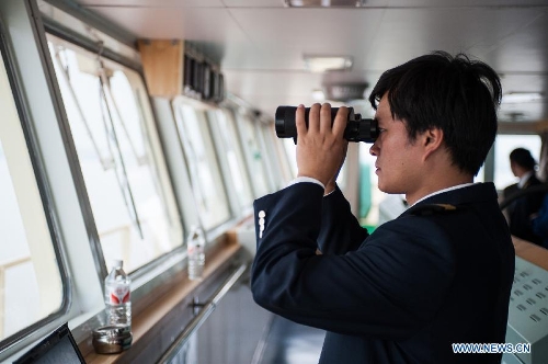 Zhu Hui checks sailing conditions using telescope aboard the Maple Star on the Yangtze River in east China's Jiangsu Province, April 24, 2013. (Xinhua/Li Mangmang) 