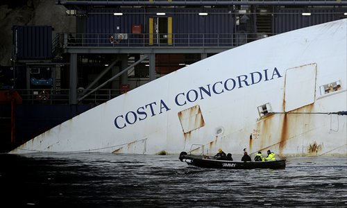 Workers in a small boat pass by the Costa Concordia cruise ship laying aground near the Italian island of Giglio on Monday. Works are going ahead as almost a year ago, the giant cruise ship crashed off the Italian coast, killing 32 people on January 13, 2012. The captain of the luxury cruise liner said Monday he had been portrayed as worse than Osama bin Laden. Photo: AFP