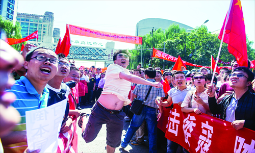 A protestor throws a water bottle into the Japanese embassy's courtyard on Saturday. Protestors continued to pelt the embassy with various objects such as eggs, apples and shoes. Photo: Li Hao/GT