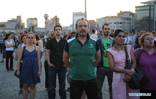 Protestors stand silently in front of Ataturk culture centre near the Taksim Square in Istanbul, Turkey, on June 18, 2013. Hundreds of people stood silently from morning to evening on Tuesday here to protest against the government. Nationwide protests began when an environmentalists' rally aiming to preserve Gezi Park adjacent to Taksim Square in Istanbul met fierce police crackdown, which triggered a wave of fiery opposition against the government's policies. (Xinhua/Lu Zhe) 