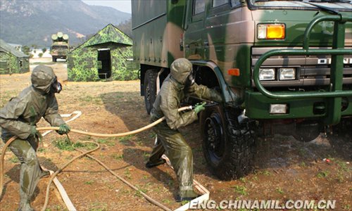 A shore-based mobile anti-ship-missile regiment under the South China Sea Fleet of the Navy of the Chinese People’s Liberation Army (PLA) organized a NBC (nuclear, biological and chemical) defense drill against actual-combat background on April 7, 2013. The picture shows the officers and men of the regiment are carrying out decontamination and detection of chemical agents in the infected “toxic” areas. (China Military Online/Sheng Yuehua, Zhao Changhong and Zheng Can)