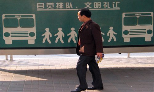 A resident passes a sign at the bus station saying 