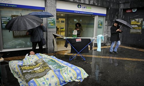 A man lies on a camping mat installed in front of a Basque government's unemployment service 