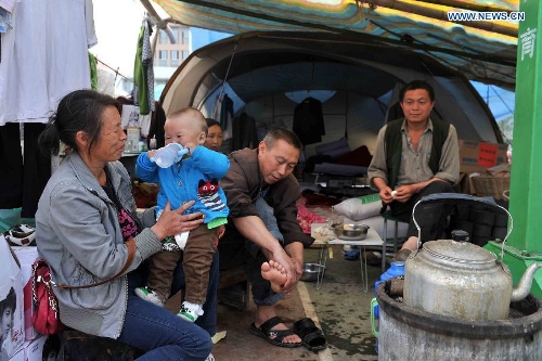 Members of a family chat outside a tent at a temporary settlement for quake-affected people in Lushan Middle School in Lushan County, southwest China's Sichuan Province, April 26, 2013. A 7.0-magnitude jolted Lushan County on April 20. (Xinhua/Li Wen) 