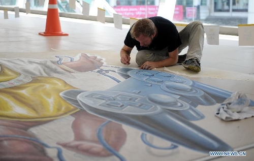 An artist draws on the ground in Bangkok, Thailand, March 2, 2013. One local artist and 19 others from over the world feast the eyes of Thai people with their 3D and 4D street paintings during the Living Arts Festival held in Bangkok.(Xinhua/Gao Jianjun) 