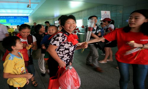 Volunteers hand out flowers to migrants at the Shanghai Railway Station Wednesday. Photo: Cai Xianmin/GT