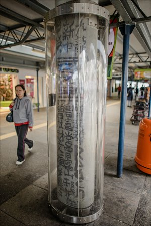 A woman walks past a plastic casing set up around a graffiti made by the late self-declared 