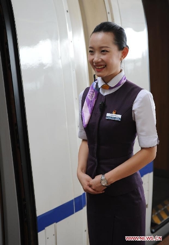 A crew member of the bullet train traveling between Nanjing and Ningbo welcomes passengers at Nanjing South Railway Station in Nanjing, east China's Jiangsu Province, July 1, 2013. The Nanjing-Hangzhou-Ningbo high-speed railway that stretches across east China's Yangtze River Delta began officially put into operation on July 1. The new high-speed railway is expected to boost the region's economy and foster the growth of tourism in the three cities it links (Xinhua/Sun Can)