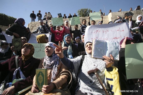 Palestinian women hold up the Koran, Islam's holy book, during a demonstration against the Israeli policeman who kick the Koran outside Damascus gate, in the old city of Jerusalem, on March 6, 2013. (Xinhua/Awad) 