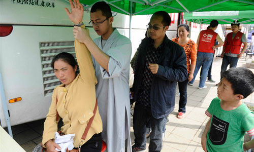 A monk examines a woman complaining of arm pain in Lushan county on April 25. Photo: Li Hao/GT