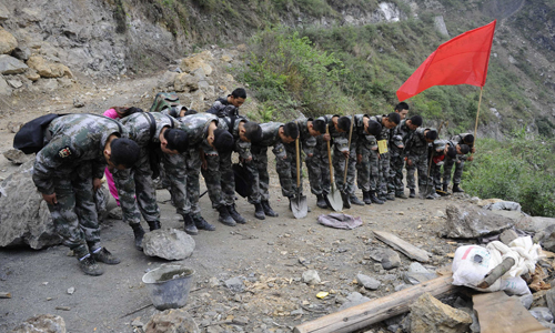 Soldiers bow their head in silent tribute to the remains of 41-year-old rescuer Zhang Guanghua, who died in a landslide on a way to Goushan village, Baoxing county, on April 23. Zhang was on his motorbike, traveling to restore electricity to the village when the landslide occurred. Photo: Li Hao/GT