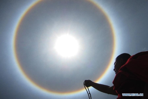 A monk looks at a solar halo occurring in Qamdo, southwest China's Tibet Autonomous Region, May 12, 2013. (Xinhua/Wen Tao) 