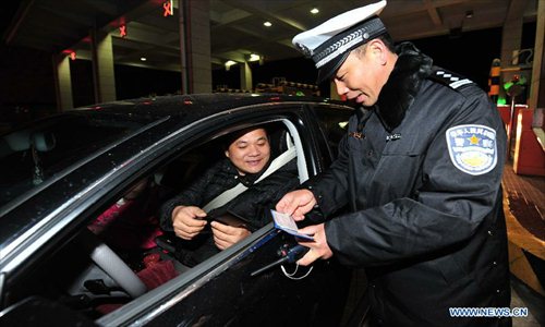 A policeman checks a driving license in Fuzhou, capital of capital of southeast China's Fujian Province, Feb. 9, 2013. The highways in China will be toll-free for passenger cars from 0:00 on Feb. 9 to 24:00 on Feb. 15 when most Chinese will go home for the Spring Festival and return to work. Photo: Xinhua