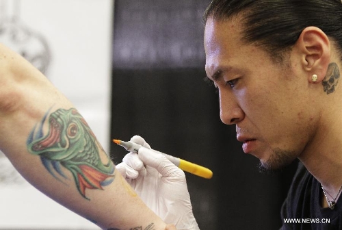 A tattoo artist works on his client's body during the 5th Vancouver tattoo and culture show in Vancouver, Canada, on April 26, 2013. The 5th Vancouver tattoo and culture show presents different tattoo art works from nearly 200 tattoo artists from across the world attracting thousands of tattoo lovers here on Friday. (Xinhua/Liang Sen) 