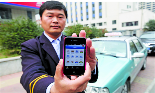 Cab driver Cao Bao holds a smartphone with the Alipay app in Ji'nan, Shandong Province on November 20. There are 20 taxis in Ji'nan preparing to offer the new payment method. Photo: CFP

