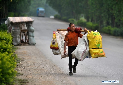 Liu Lingchao carries some bags of used bottles near his 
