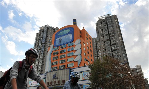 Bicyclers ride past an 11-story building made to look like a hand holding a mobile phone in Kunming, Yunnan Province on Sunday. The building is said to be the city's largest shopping center for mobile phones. Photo: CFP