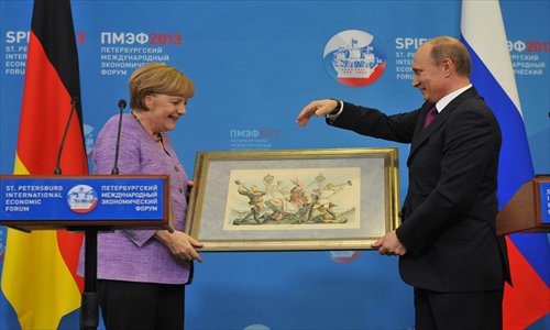 Russia's President Vladimir Putin (R) presents Germany's Chancellor Angela Merkel with an old lithograph dedicated to the signing of a Russian-German trade agreement in 1894 at a press conference during an International Economic Forum in St. Petersburg on June 21. Photo: IC