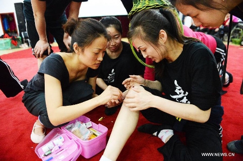 Members of the dancing team of the Harbin Disabled Art Group help another team member with the bleeding in a dancing room in Harbin, capital of northeast China's Heilongjiang Province, May 14, 2013. The art group, which is made up of 18 deaf-mutes, was founded in 2011. Bonded by the love for dancing, all the members in the group take trainings and create dancing programs together, and have also brought many of their dancing programs on stage in two years. (Xinhua/Wang Kai) 