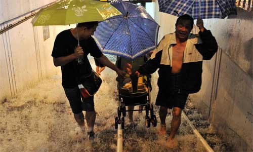 Three pedestrians carry a baby carriage at an underpass in Beijing, capital of China, July 21, 2012. Photo: Xinhua
