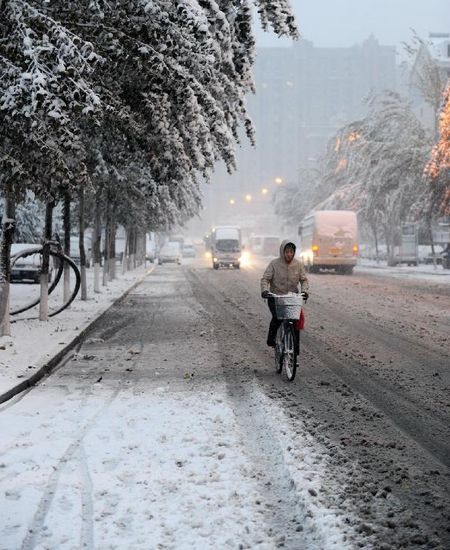 A citizen rides a bike on a snow-covered road in Changchun, capital of Northeast China's Jilin Province, October 22, 2012. Most parts of Jilin witnessed snowfall on Monday. Photo: Xinhua