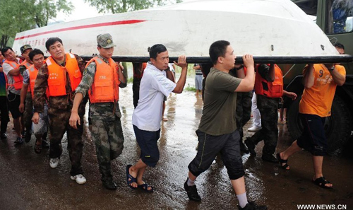 Soldiers and villagers carry a boat in Daweizi village of Xiuyan, northeast China's Liaoning Province, Aug. 5, 2012. Nearly 1.46 million people in Liaoning were affected by heavy rains and floods caused by Typhoon Damrey, authorities said Sunday. Photo: Xinhua