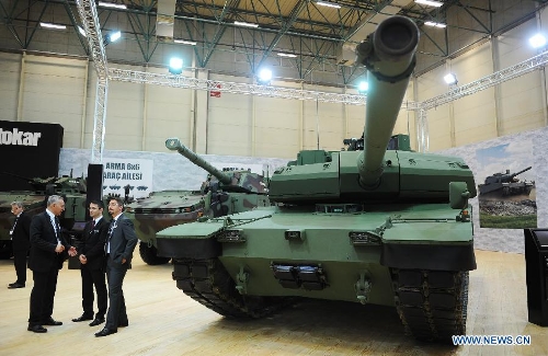 Guests consult near the ALTAY tank shown by OTOKAR company of Turkey in Istanbul, Turkey, May 7, 2013. The 11th International Defence Industry Fair was opened on Tuesday, with 781 companies from 82 countries and regions attending the four-day fair. (Xinhua/Lu Zhe) 