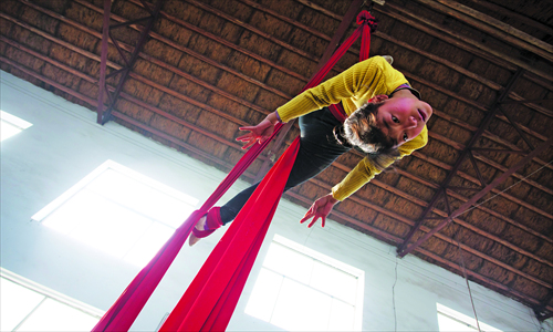 A girl trains lifting herself off the ground on a silk ribbon. Photo: CFP