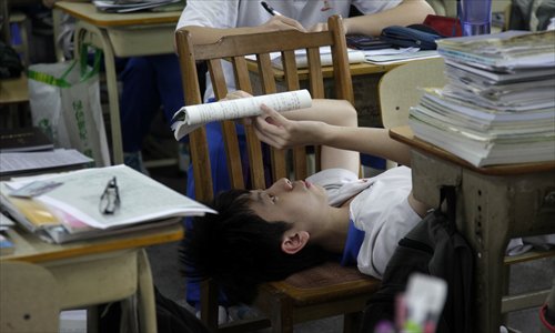 A student at the No.47 Middle School in Guangzhou, Guangdong Province, reads a book while lying down in the classroom on May 23, a few days before the National College Entrance Examinations. Photo: CFP 
