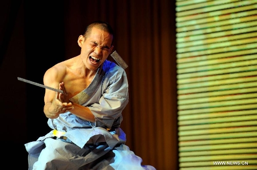 A performer of the Yandong Shaolin Kungfu troupe breaks a steel sheet by hitting his head during a performance held at the Worker's Cultural Palace, Taiyuan, capital of north China's Shanxi Province, July 6, 2013. The martial art troupe have their performers trained in the renowned Shaolin Temple, and staged performances worldwide in the hope of promoting Shaolin-style martial arts and Chinese culture. (Xinhua/Fan Minda)&nbsp; 
