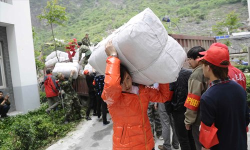 Volunteers distribute quilts from a truck in Baoxing county on April 24. Photo: Li Hao/GT