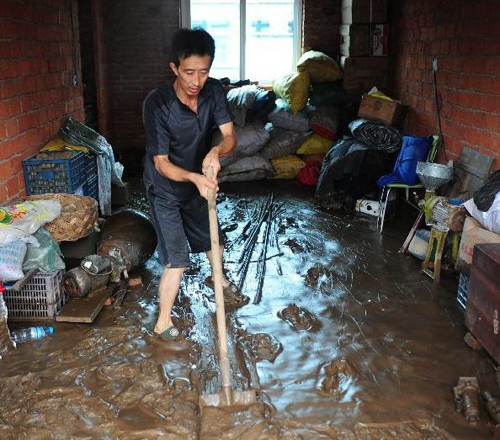 A villager cleans the mud inside his house in Daweizi village of Xiuyan County, northeast China's Liaoning Province, Aug. 5, 2012. Nearly 1.46 million people in Liaoning were affected by heavy rains and floods caused by Typhoon Damrey, authorities said Sunday. Photo: Xinhua