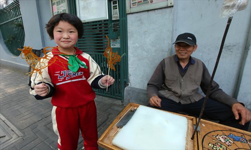 A happy child shows off a freshly-made sugar cock and a tiger. Photo: Cai Xianmin/GT