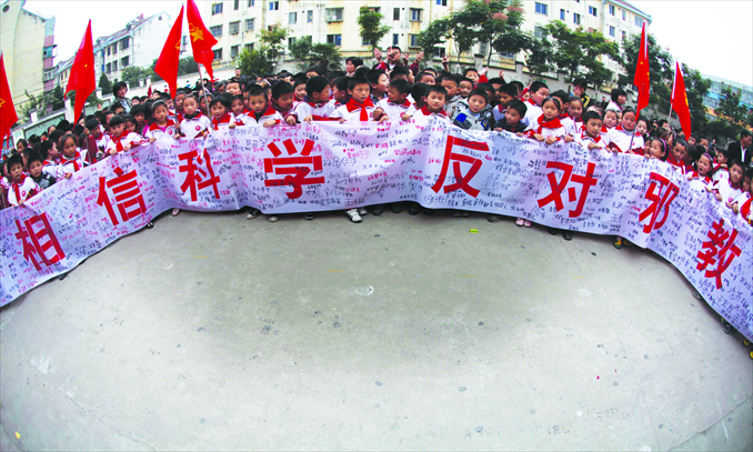Students of Danhua Primary School in Haozhou, Anhui Province, hold a banner with signatures against cults, on October 13, 2011. Photo: IC
