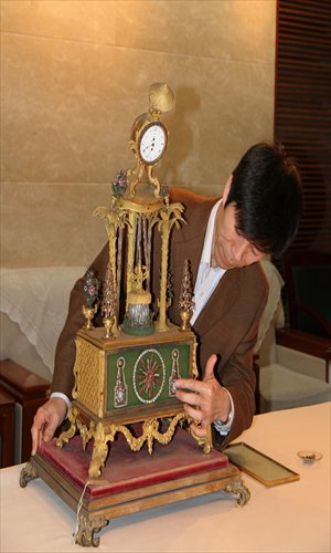 A Forbidden City museum expert studies an antique clock on Sunday that was damaged when a vandal smashed a window. Photo: Courtesy of the Forbidden City