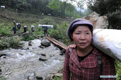 A woman carrying disaster relief supplies waits for her son as walking in the mountain in quake-hit Shifeng Village of Lushan County, southwest China's Sichuan Province, April 22, 2013. The road linking the Shifeng Village with the outside had been destroyed by a 7.0-magnitude earthquake on April 20. Local villagers set up a 300-member group to climb mountains to get relief supplies outside and then return to the village. Over 40 tonnes of materials had been transported and distributed to over 2,000 villagers. (Xinhua/Li Ziheng) 