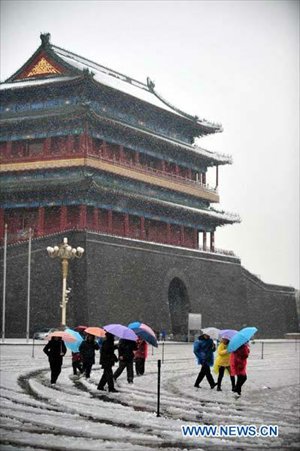 Tourists shelter from the sleet under umbrellas as as they walk near the Tian'anmen Square in Beijing, capital of China, on November 4, 2012. The capital city had witnessed snowfall and sleet since Saturday night as cold current swept north China and dropped temperature. Photo: Xinhua 