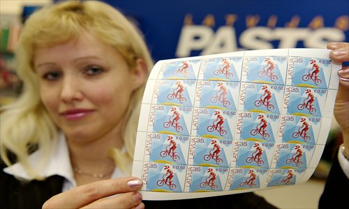 A post worker shows the first Latvian stamps denominated in both lats and euros in Riga on Wednesday. Unfazed by the eurozone crisis, Latvia is poised to pass key legislation on Thursday, paving the way for a request for EU approval of its entry as the eurozone's 18th member on January 1, 2014. Photo: AFP