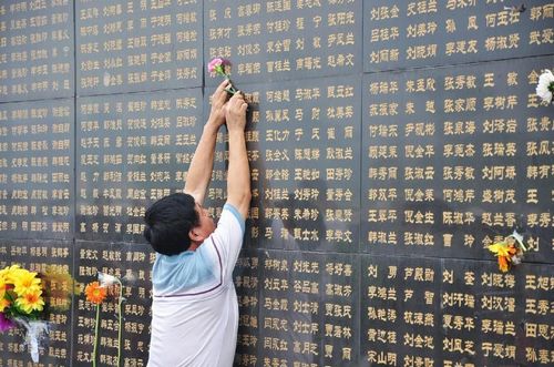 A man puts a flower on the name of his loved one who was killed in the 1976 earthquake on the memorial wall bearing the names of the earthquake victims in Tangshan, North China's Hebei Province, July 28, 2012. Saturday marked the 36th anniversary of the Tangshan earthquake. Tangshan lost 240,000 lives to a devastating 7.8-magnitude earthquake on July 28, 1976, which was believed to be one of the deadliest natural disasters of the 20th century. Photo: Xinhua
