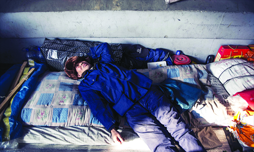 Tang lies on his quilt under the bridge. The sunshine leaking through the cracks of the bridge in the afternoon provides him with the most warmth he'll get in a day.  Photo: Li Hao/GT