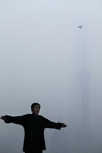 A person performs morning exercise in front of the barely visible Oriental Pearl TV Tower, which is shrouded by smog, in Shanghai on Friday. Photo: IC