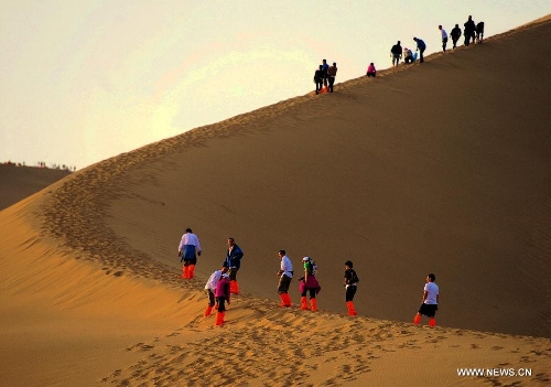 Tourists visit the scenic spot of the Mingsha Mountain and Crescent Spring in Dunhuang City, northwest China's Gansu Province, May 21, 2013. Dunhuang has received about 749,200 tourists in the first four months of 2013, increasing 58.63 percent year on year. (Xinhua/Nie Jianjiang)  