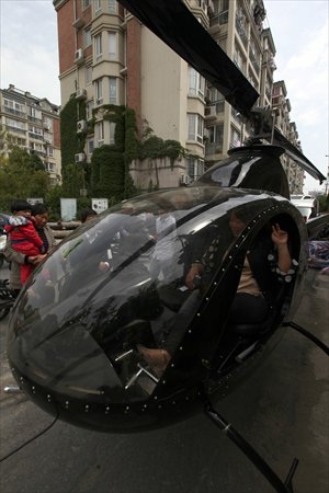 A woman sits inside a private helicopter parked near a residential building in Yancheng, East China's Jiangsu Province on Tuesday. The helicopter was reportedly bought by a man surnamed Wang from Northeast China's Jilin Province on Tuesday for 2 million yuan ($324,800). China's market for private aircraft has been booming in recent years as the nation's ballooning wealthy population looks for luxury items to showcase their social status. Photo: CFP