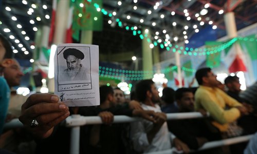 An Iranian man holds a photo of late Ayatollah Khomeini, while listening to Rouhani delivering a speech at Khomeini's mausoleum in a suburb of Tehran on Tuesday. 
Khomeini died on June 3, 1989 aged 86. The Islamic state that was founded in 1979 on a vision of establishing a Muslim democracy lives on, but the country faces daunting challenges, analysts say. Photo: AFP