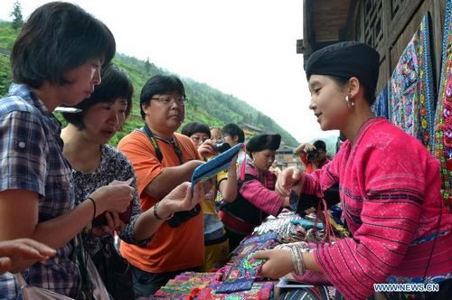 Tourists select souvenirs in the Huangluo Village of the Yao ethnic group in Guilin, South China's Guangxi Zhuang Autonomous Region, July 15, 2012. Tourist volume in scenic zones of Guilin soared as the summer vacation started. Photo: Xinhua