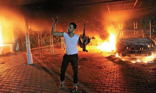 An armed man waves his rifle as buildings and cars are engulfed in flames after being set on fire inside the US consulate compound in Benghazi late Tuesday. An armed mob attacked the US consulate in Benghazi and set fire to the building. Photo: AFP