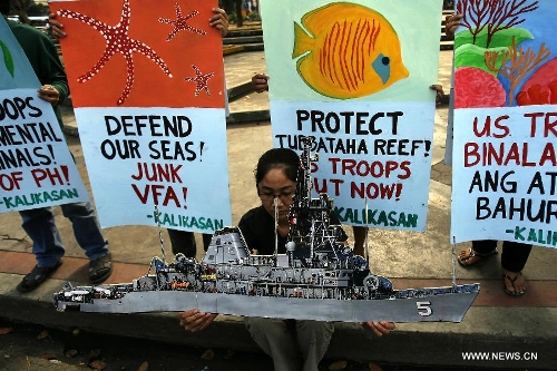 An activist holds a picture of the USS Guardian during a rally near the U.S. Embassy in Manila, the Philippines, Jan. 21, 2013. The protesters called for the pullout of U.S. troops in the Philippines after the U.S. Navy minesweeper USS Guardian (MCM 5) ran aground on Tubbataha Reef. (Xinhua/Rouelle Umali) 